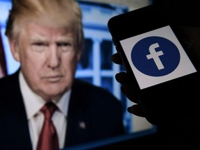 In this photo illustration, a phone screen displays a Facebook logo with the official portrait of former US President Donald Trump on the background, on May 4, 2021, in Arlington, Virginia