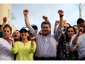 In this file photo, Honduran President Juan Orlando Hernandez gestures during a rally with supporters outside the Presidential House. He flouted his country’s constitution to get re-elected in 2017. And U.S. courts have labelled him a co-conspirator in a narcotics ring run by his brother.