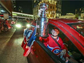 A Montreal Canadiens fan holds a Stanley Cup replica out the car window as his friend drives through throngs of Habs fans outside the Bell Centre after a four-game sweep of the Winnipeg Jets June 7, 2021.