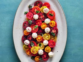 Miniature tomatoes are drizzled with olive oil, garlic and lemon juice before being topped with balls of labneh and fresh herbs.