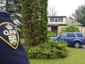 An OPP officer stands guard outside a home in Rossmore, Ont., south of Belleville, on Friday.