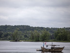 An unidentified man adjusts a Canadian flag flying on his boat while on the Ottawa River by Petrie Island Beach on Saturday.