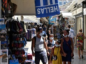 File photo/ Tourists wearing protective face masks walk in Athens' main commercial district.