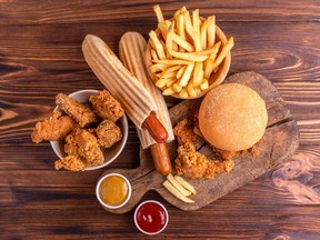 Delicious but unhealthy food with ketchup and mustard on vintage cutting board. Fast carbohydrates, junk and fast food. Warm wooden background. Getty Images/iStockphoto