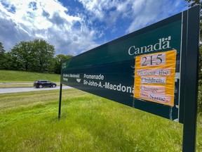 A sign in memory of the 215 children whose remains were found at the grounds of the former Kamloops Indian Residential School in Kamloops, B.C., was affixed to the western entrance sign of the Sir John A. Macdonald Parkway on Thursday.