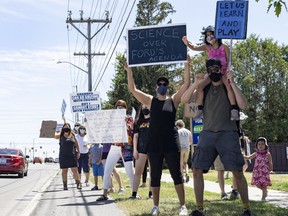 Sarah and Maxime Bedard and their daughter Eva joined about 50 people in a school-closures protest near the office of Nepean MPP Lisa MacLeod on Thursday