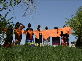 A group of spectators looks on while speakers talk during a vigil following the discovery of 215 buried children on the site of a former residential school in British Columbia. The vigil was held at the grounds of the former Muskowekwan Indian Residential School on Muskowekwan First Nation in Saskatchewan on June 1, 2021.