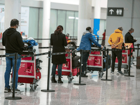 International travellers await transportation to a COVID-19 quarantine hotel after arriving at Pearson International Airport, February 24, 2021.