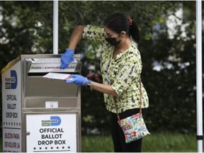 An election official wearing a protective mask and gloves places a mail-in ballot in a drop box at an early voting polling location for the 2020 Presidential election in Miami, on Oct. 19, 2020.  Republicans were decidedly unhappy with the outcome of the November election and continue to look for ways of undermining the result.