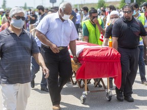 Four Canadian flag-draped coffins for the members of the Afzaal family, killed last Sunday when a vehicle jumped a curb at an intersection and struck them in what police allege was a deliberate attack, are wheeled to the front of a large crowd that gathered Saturday at the Islamic Centre of Southwest Ontario for an outdoor funeral. Photograph taken on Saturday June 12, 2021. Mike Hensen/The London Free Press/Postmedia Network