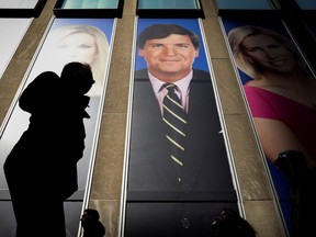 People pass by a promo of Fox News host Tucker Carlson on the News Corporation building in New York, U.S., March 13, 2019.