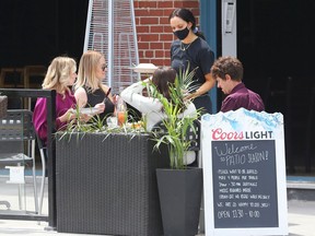 A server brings out food to patio goers at Johnny Farina on Elgin St, June 11, 2021..