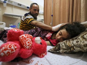 Palestinian Ryad Eshkuntana, checks his daughter Suzy, as they receive medical care at Al-Shifa hospital in Gaza City, on May 19, 2021, after his wife and other children were killed in an Israeli air strike.