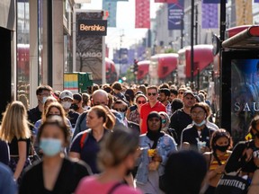 Pedestrians, some wearing face coverings due to Covid-19, walk past shops on Oxford Street in central London on June 7, 2021.