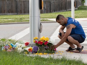 A man brings flowers and pays his respects near the scene where an attacker driving a pickup truck struck and killed four members of a Muslim family in London, Ont. on June 7.