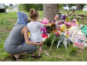 Families pay their respects on June 8 at a makeshift memorial near the site where a man driving a pickup truck struck and killed four members of a Muslim family in London, Ont.