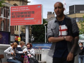 A pedestrian walks past an electronic information board displaying a COVID-19 information relating to a "variant of concern in the area" in Blackburn, northwest England, on June 16, 2021.