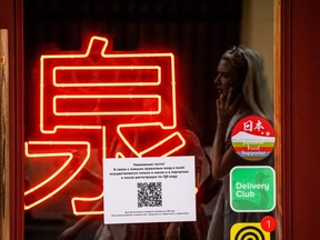 A picture taken on June 22, 2021, in Moscow, shows the door of a restaurant with a sign indicating that guests must register in the restaurant via a QR code before taking a seat.