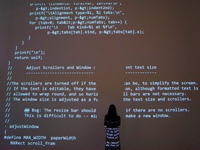 A person poses in front of a projection of source code during a media preview at Sotheby's on June 24, 2021, in New York, for Sotheby's NFT Auction of Sir Tim Berners-Lee "Source Code for the World Wide Web," which will be offered for sale as an NFT.