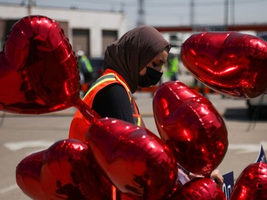 A volunteer places a sign outside the Islamic Centre of Southwest Ontario, next to heart-shaped balloons, before a funeral of the Afzaal family that was killed in what police describe as a hate-motivated attack, in London, Ontario, Canada June 12, 2021. REUTERS/Carlos Osorio ORG XMIT: GDN