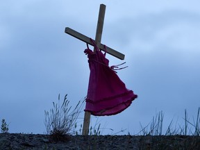 A child's red dress hangs on a stake near the grounds of the former Kamloops Indian Residential School after the remains of 215 children, some as young as three years old, were found at the site.