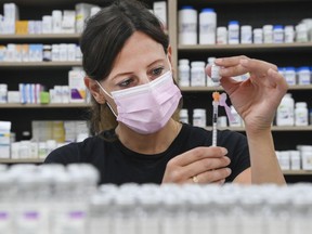 FILE: Barbara Violo, pharmacist and owner of The Junction Chemist Pharmacy, draws up a dose of the Pfizer-BioNTech COVID-19 vaccine, in Toronto, Friday, June 18, 2021.