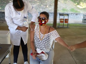 A woman holds the hand of her relative as she receives the coronavirus disease (COVID-19) vaccine during the mass vaccination part of the "Paqueta Vacinada" (Paqueta vaccinated) project, that aims to vaccinate the whole population over 18 years old on Paqueta Island in Guanabara Bay, in Rio de Janeiro, Brazil June 20, 2021.