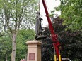 The statue of Sir John A. Macdonald is lifted off the pedestal base in City Park in the morning of Friday, June 18. Kingston city council voted 12-1 to remove the statue at a special meeting on Wednesday. The city plans to place the statue at Macdonald's burial plot in Cataraqui Cemetery at a later date.