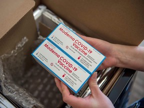 A person unpacks a special refrigerated box of the Moderna vaccine.