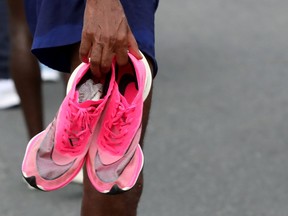 Athlete holding Nike Vaporfly shoes after a race.