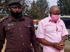 FILE PHOTO: Paul Rusesabagina, portrayed as a hero in a Hollywood movie about Rwanda's 1994 genocide, is escorted in handcuffs into a courtroom, in Kigali, Rwanda October 20, 2020.