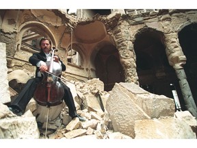 What behaviours do we normalize during times of deep crisis? This file photo dated Sept. 12 1992 shows cellist Vedran Smailovic playing Strauss in the bombed National Library in Sarajevo during the Bosnian War.