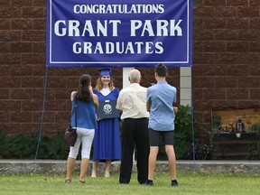 A family uses a backdrop in front of Grant Park High School for photographs following a graduation ceremony in Winnipeg.