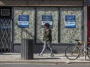 File: A pedestrian wearing a mask walks past a shuttered business now for lease on Toronto's Queen Street during the Covid 19 pandemic