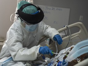 A member of the medical staff wearing full PPE brushes a patient's teeth in the COVID-19 intensive care unit.