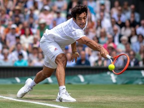 Cristian Garin of Chile stretches to play a backhand in his Men's Singles Fourth Round match against Novak Djokovic of Serbia during Day Seven of The Championships - Wimbledon 2021 at All England Lawn Tennis and Croquet Club on Monday in London, England.