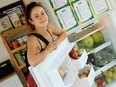 Parkdale Food Centre employee Alexia Smith shows what's inside the new community fridge and pantry outside the centre.