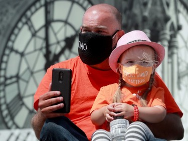 Octavia Woodroffe, 3, wears a little "Every Child Matters" mask while watching the speakers with her father, Jay Woodroffe, at the rally on Parliament Hill on Saturday.