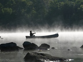 FILE: Fishing from a canoe on a misty morning.