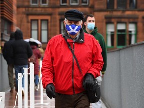 A man in a face mask follows a one-way queuing system as he arrives to vote at a polling station at a school in Scottish Parliament elections in Glasgow on May 6, 2021.