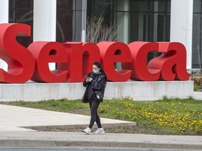 Seneca Colleges Scarborough Campus TORONTO, ONTARIO: MAY 5, 2021—PANDEMIC--A pedestrian wearing a mask walks past Covid 19 signage at Scarborough's Woodside Square Mall during the Covid 19 pandemic, Wednesday May 5, 2021. [Peter J Thompson] [National Post story by TBA/National Post]