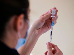 FILE: A health worker fills a syringe with a dose of the Pfizer-BioNTech vaccine.