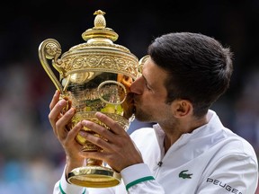 Serbia's Novak Djokovic kisses the winner's trophy after beating Italy's Matteo Berrettini during their men's singles final match on the thirteenth day of the 2021 Wimbledon Championships at The All England Tennis Club in Wimbledon, southwest London, on July 11, 2021.