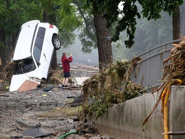 A man standing next to a destroyed car takes pictured of the devastated area after the floods caused major damage in Bad Neuenahr-Ahrweiler, western Germany, on July 16, 2021.