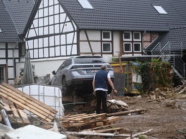 A resident stands next to debris and a destroyed car in Iversheim, near Bad Muenstereifel, western Germany, on July 16, 2021, following heavy rains.