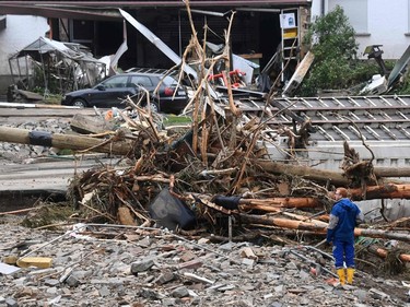 A man stands in front of a pile of driftwood amid rubble after floods caused major damage in Schuld near Bad Neuenahr-Ahrweiler, western Germany, on July 16, 2021.