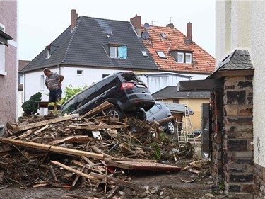 A man stands next to piled up debris and damaged cars in a street in Bad Neuenahr-Ahrweiler, western Germany, on July 16, 2021, after heavy rain hit parts of the country, causing widespread flooding and major damage.