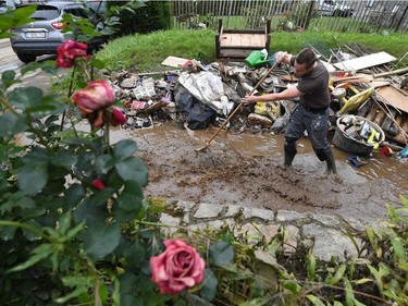 A resident stands in flood waters as he tries to clear up following heavy rains and floods in the town of Rochefort on July 17, 2021.