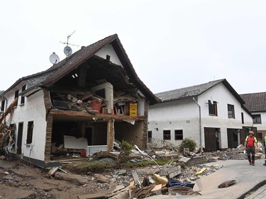 Two men walk past destroyed houses after floods caused major damage in Schuld near Bad Neuenahr-Ahrweiler, western Germany, on July 17, 2021.