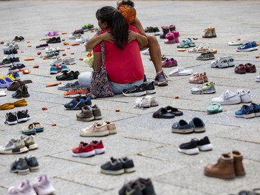 Kindergarten teacher Jane Kigutaq, wearing the red shirt, is consoled by an unidentified woman while sitting among children's shoes place in memory ofl to the discovery of victims of the residential school system.